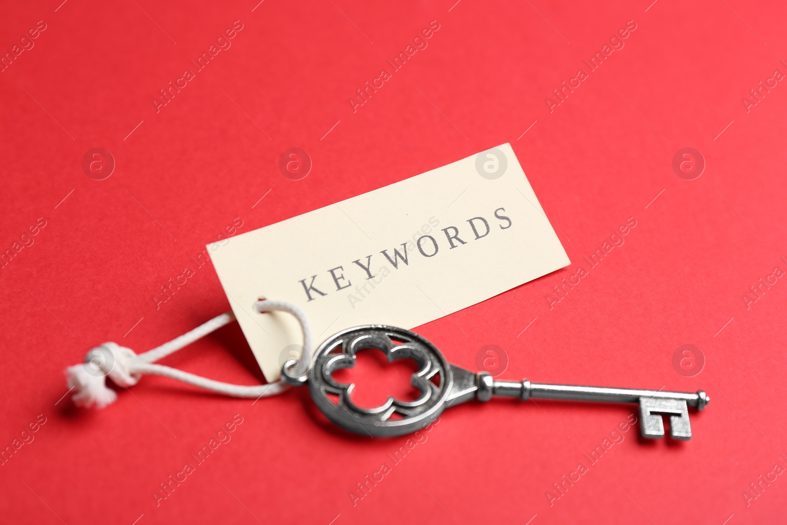 Photo of Vintage key and tag wIth word KEYWORDS on red background