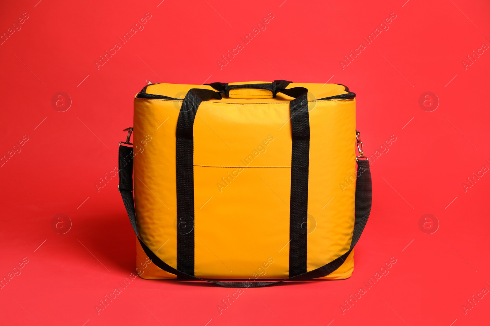 Photo of Modern yellow thermo bag on red background