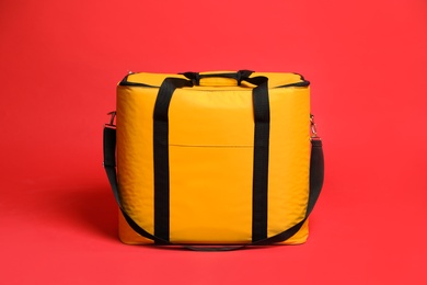 Photo of Modern yellow thermo bag on red background