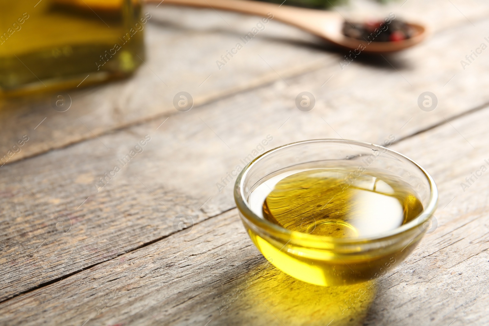 Photo of Bowl of rosemary oil on wooden table