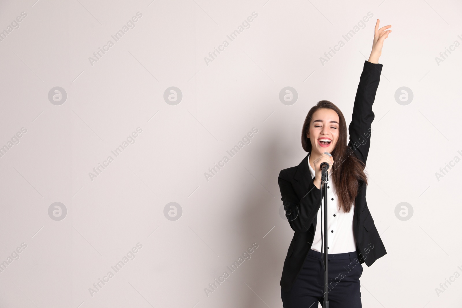 Photo of Young woman singing in microphone on color background. Space for text