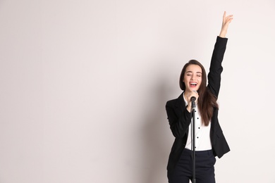 Young woman singing in microphone on color background. Space for text