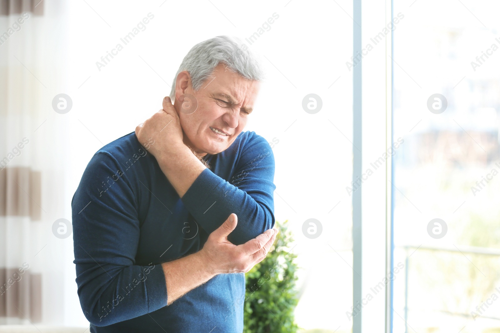 Photo of Mature man suffering from neck pain at home