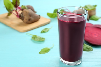 Photo of Fresh beet juice in glass on blue wooden table. Space for text