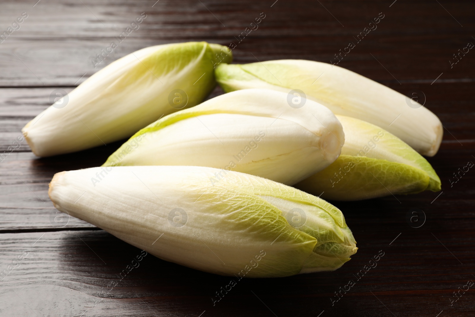 Photo of Raw ripe chicories on wooden table, closeup