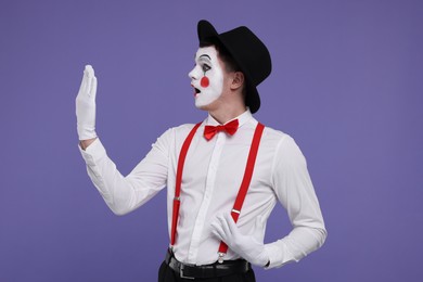 Photo of Mime artist making excited face on purple background