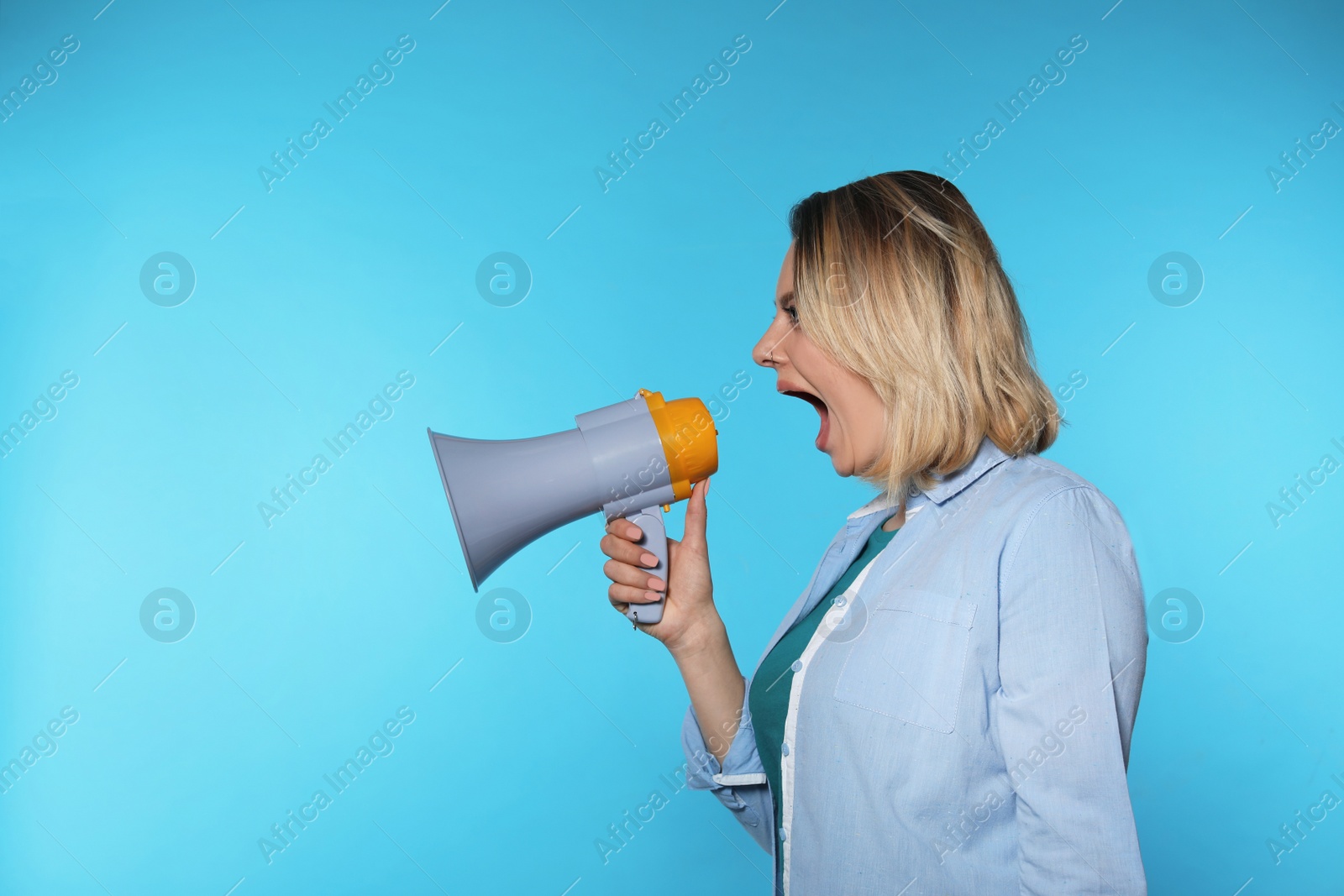 Photo of Portrait of emotional woman using megaphone on color background. Space for text