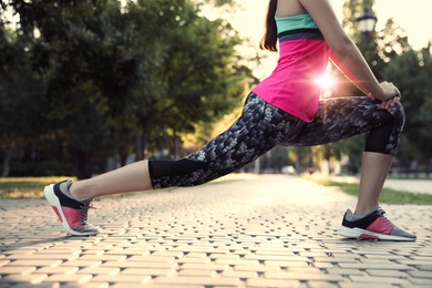 Young woman stretching before morning run in park, closeup
