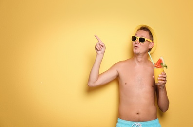 Shirtless man with glass of cocktail on color background