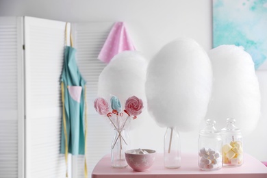 Photo of Tasty cotton candy and other sweets on table in room. Space for text