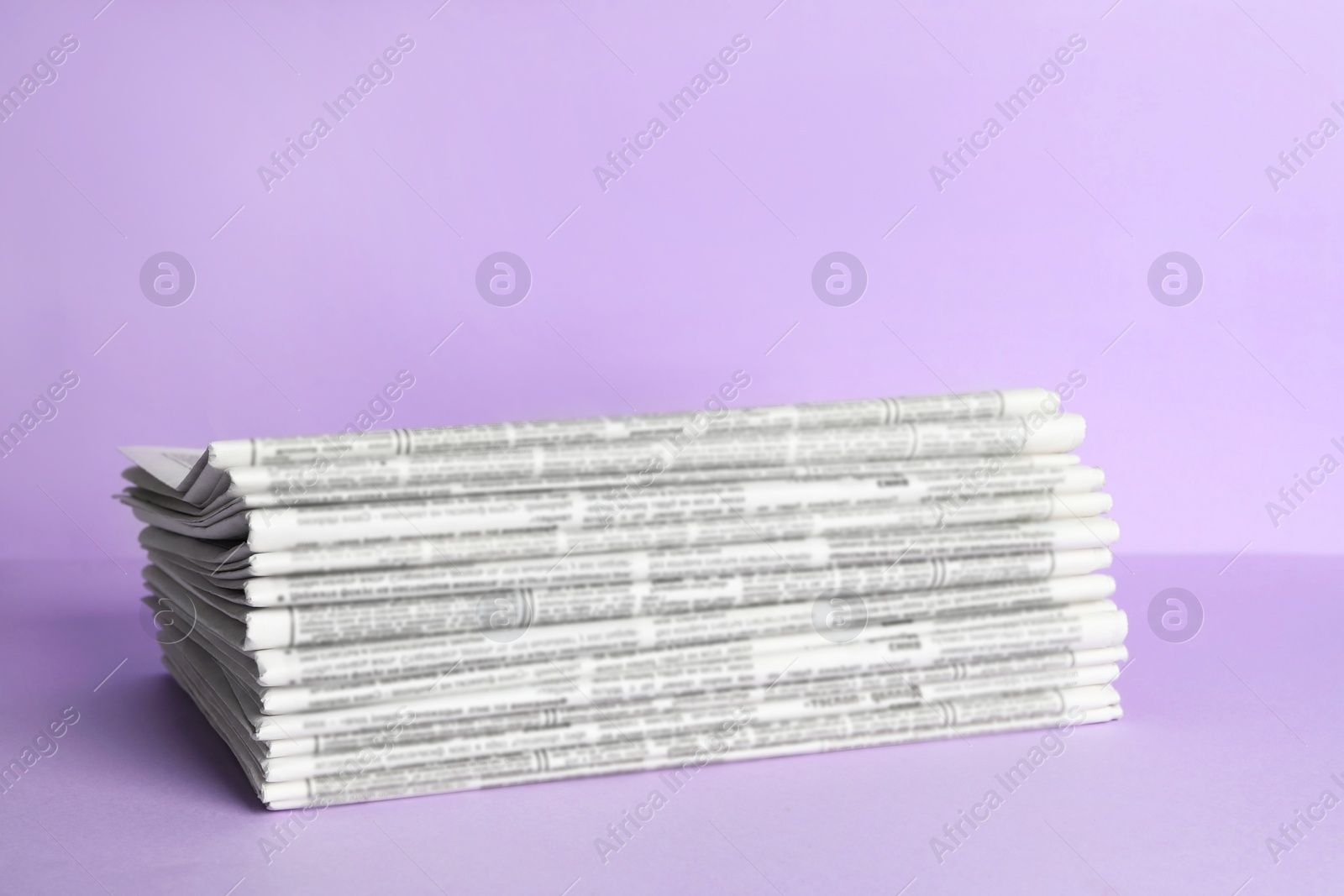 Photo of Stack of newspapers on light violet background. Journalist's work