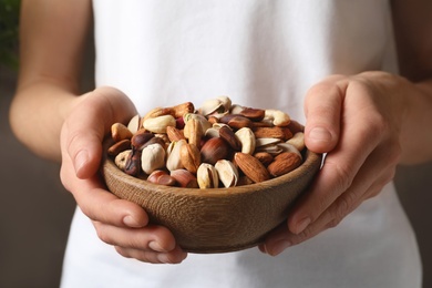 Photo of Woman holding bowl with organic mixed nuts, closeup