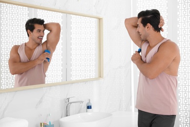 Handsome young man applying deodorant in bathroom