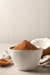 Natural coconut sugar in bowl on white wooden table