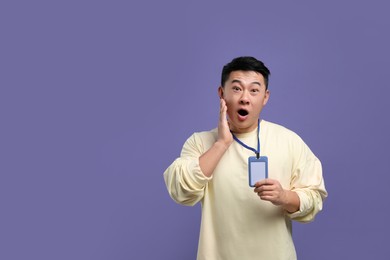 Emotional asian man with vip pass badge on purple background. Space for text