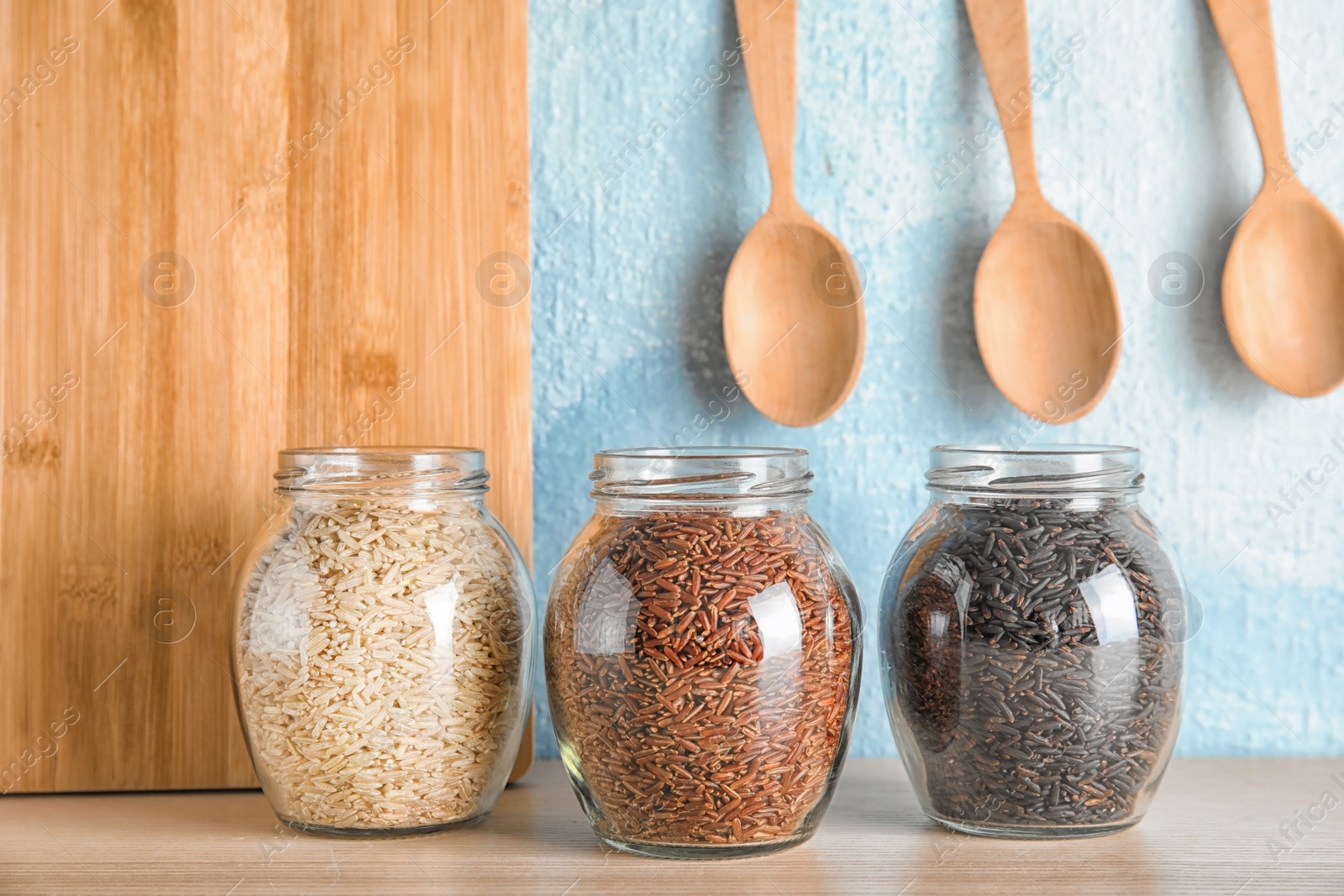 Photo of Jars with different types of rice on table in kitchen