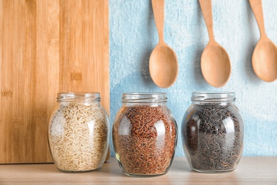 Jars with different types of rice on table in kitchen