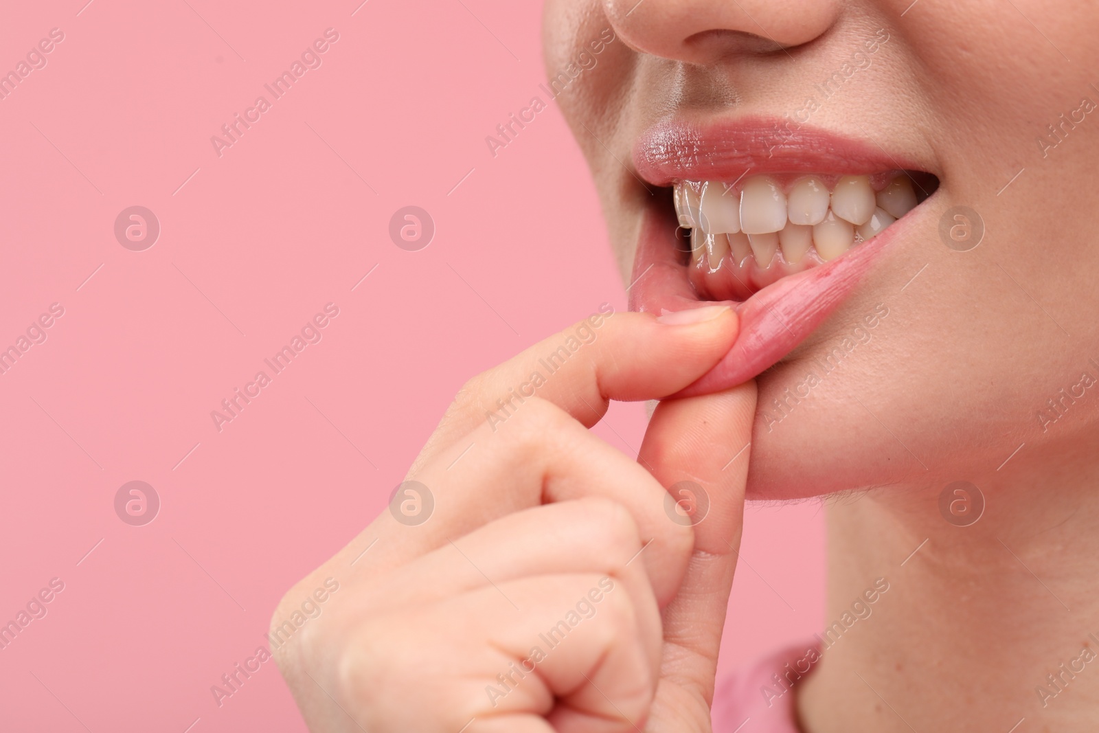 Photo of Beautiful woman showing her clean teeth on pink background, closeup. Space for text