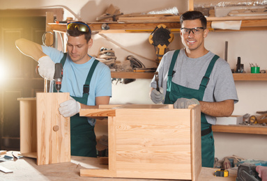Photo of Professional carpenters assembling wooden cabinet in workshop
