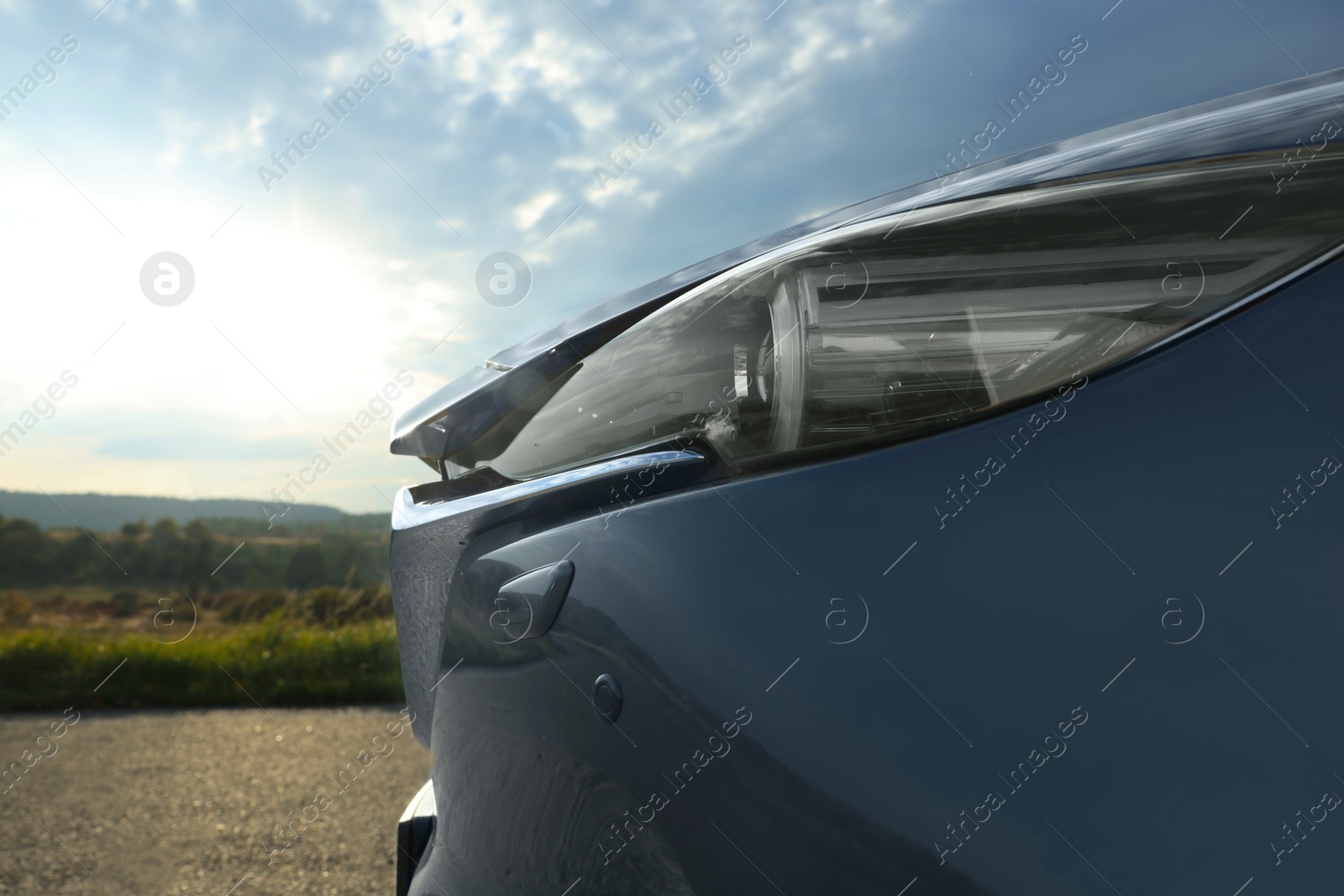 Photo of Black modern car parked outdoors, closeup of headlight