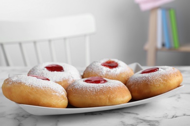 Hanukkah doughnuts with jelly and sugar powder on white marble table indoors, space for text