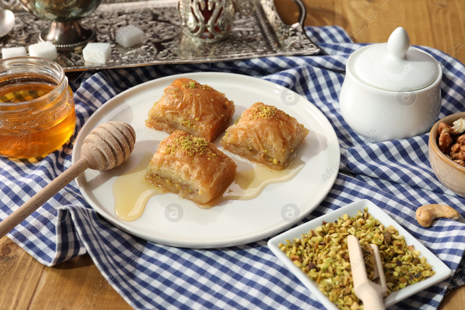 Photo of Delicious sweet baklava with pistachios and honey on table