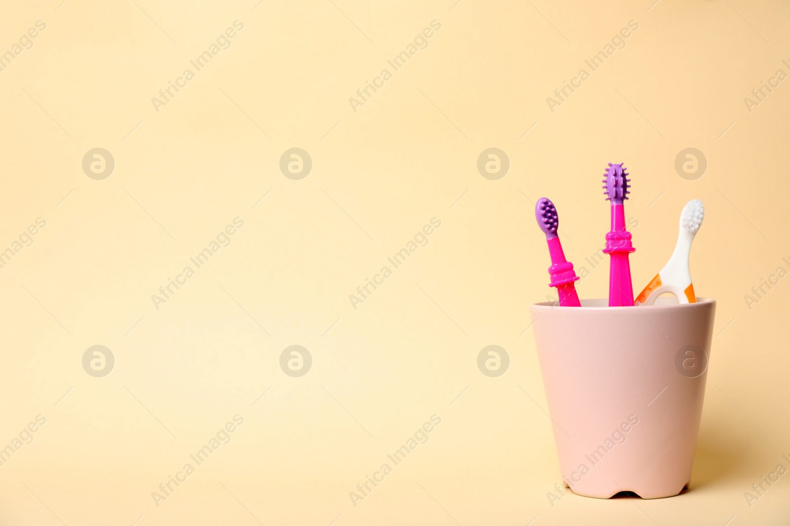 Photo of Baby toothbrushes in holder and space for text on color background