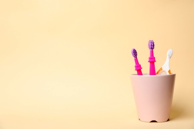 Baby toothbrushes in holder and space for text on color background