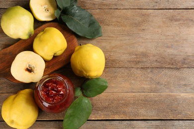 Photo of Delicious quince jam and fruits on wooden table, flat lay. Space for text