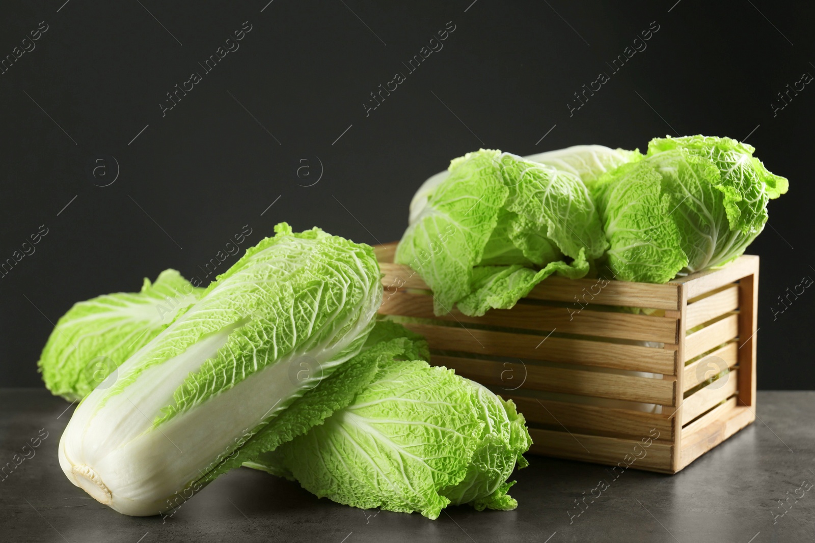 Photo of Fresh ripe Chinese cabbages and wooden crate on grey table