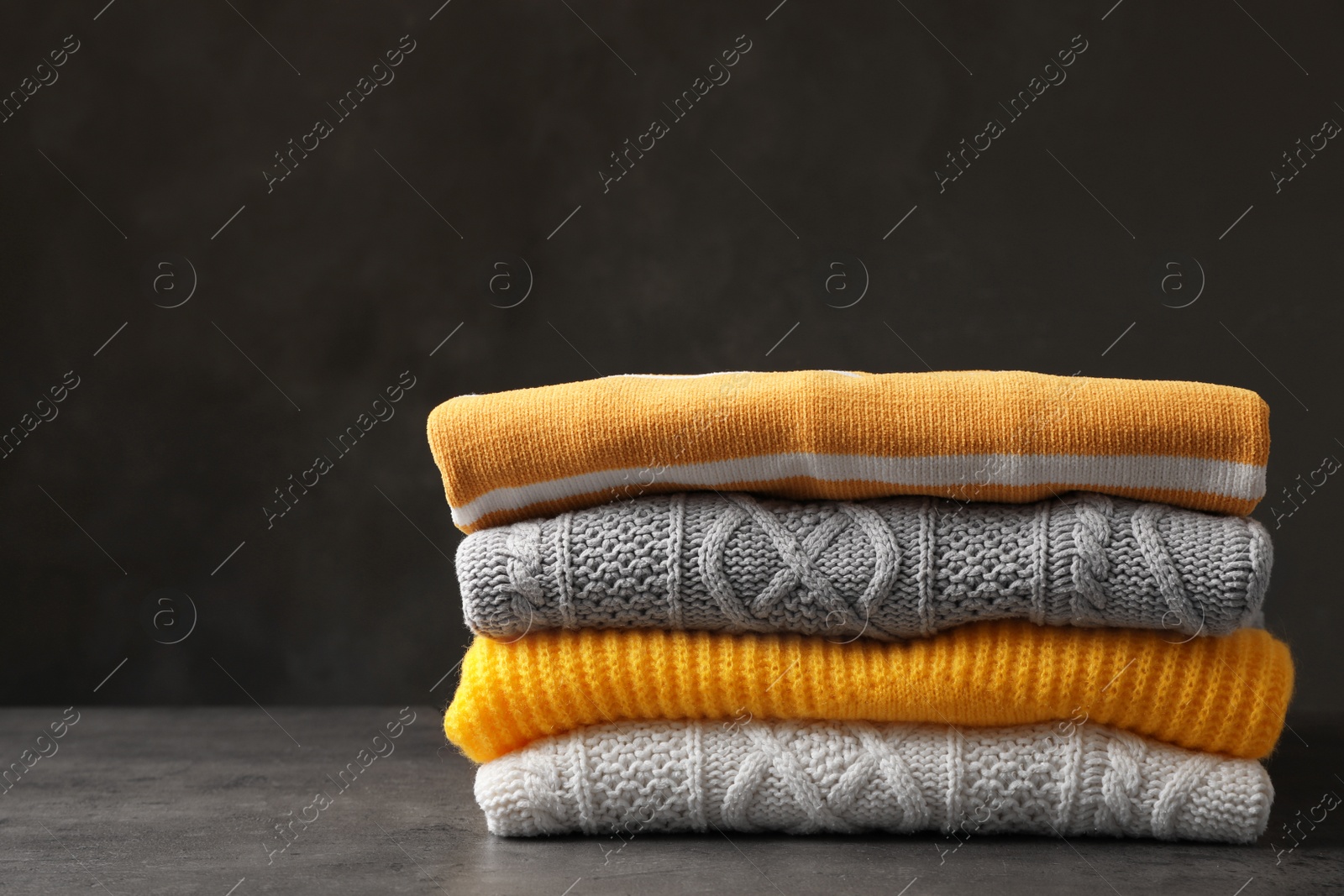 Photo of Stack of folded knitted sweaters on table. Space for text