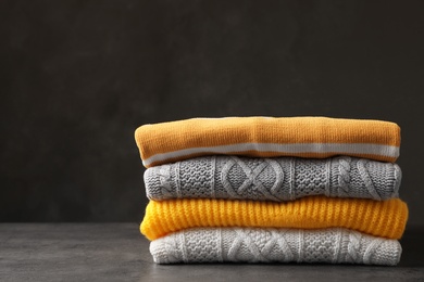 Photo of Stack of folded knitted sweaters on table. Space for text