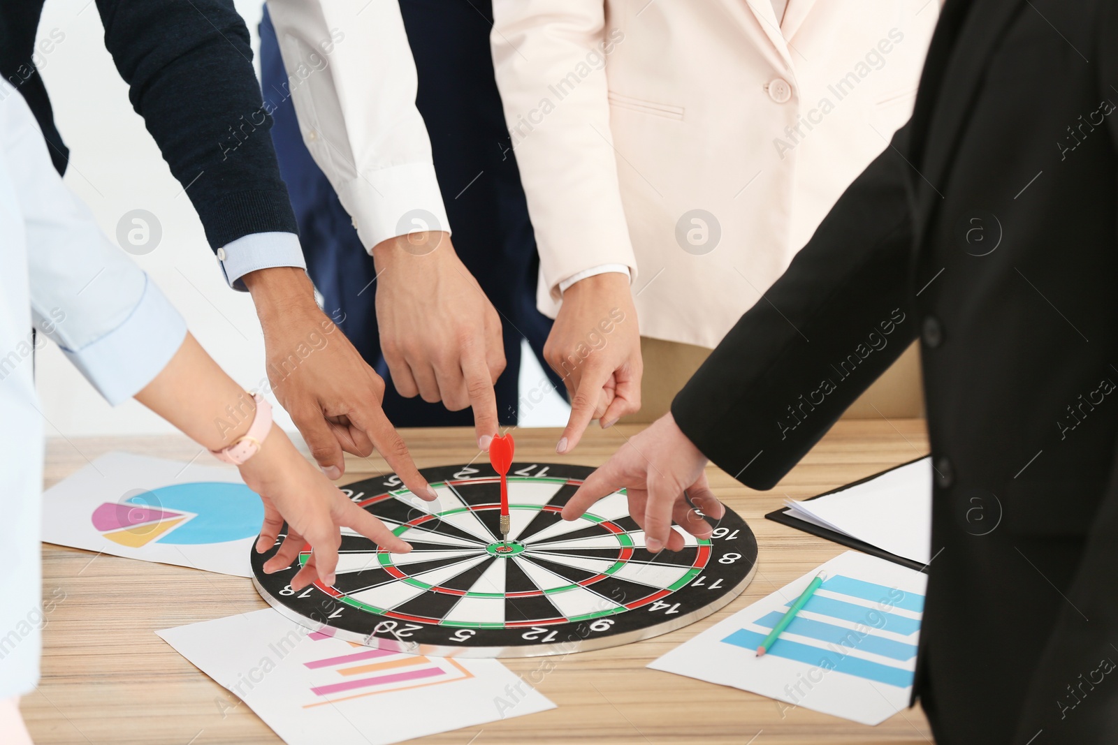 Photo of Employees pointing on dart board lying on table, closeup