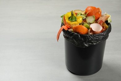 Photo of Trash bin with natural garbage on light background, space for text. Composting of organic waste