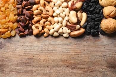 Photo of Different dried fruits and nuts on wooden background, top view. Space for text