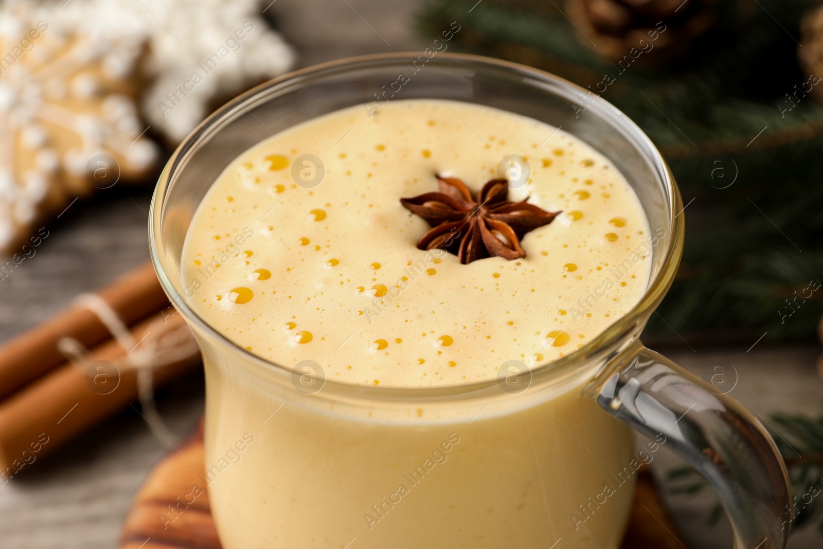 Photo of Glass of delicious eggnog with anise star on table, closeup