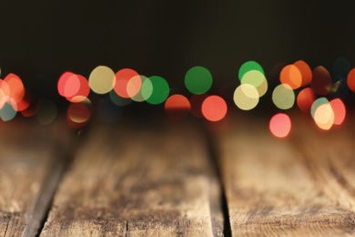 Blurred view of colorful lights on wooden table, space for text