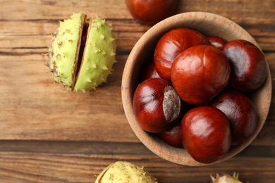 Photo of Horse chestnuts on wooden table, flat lay