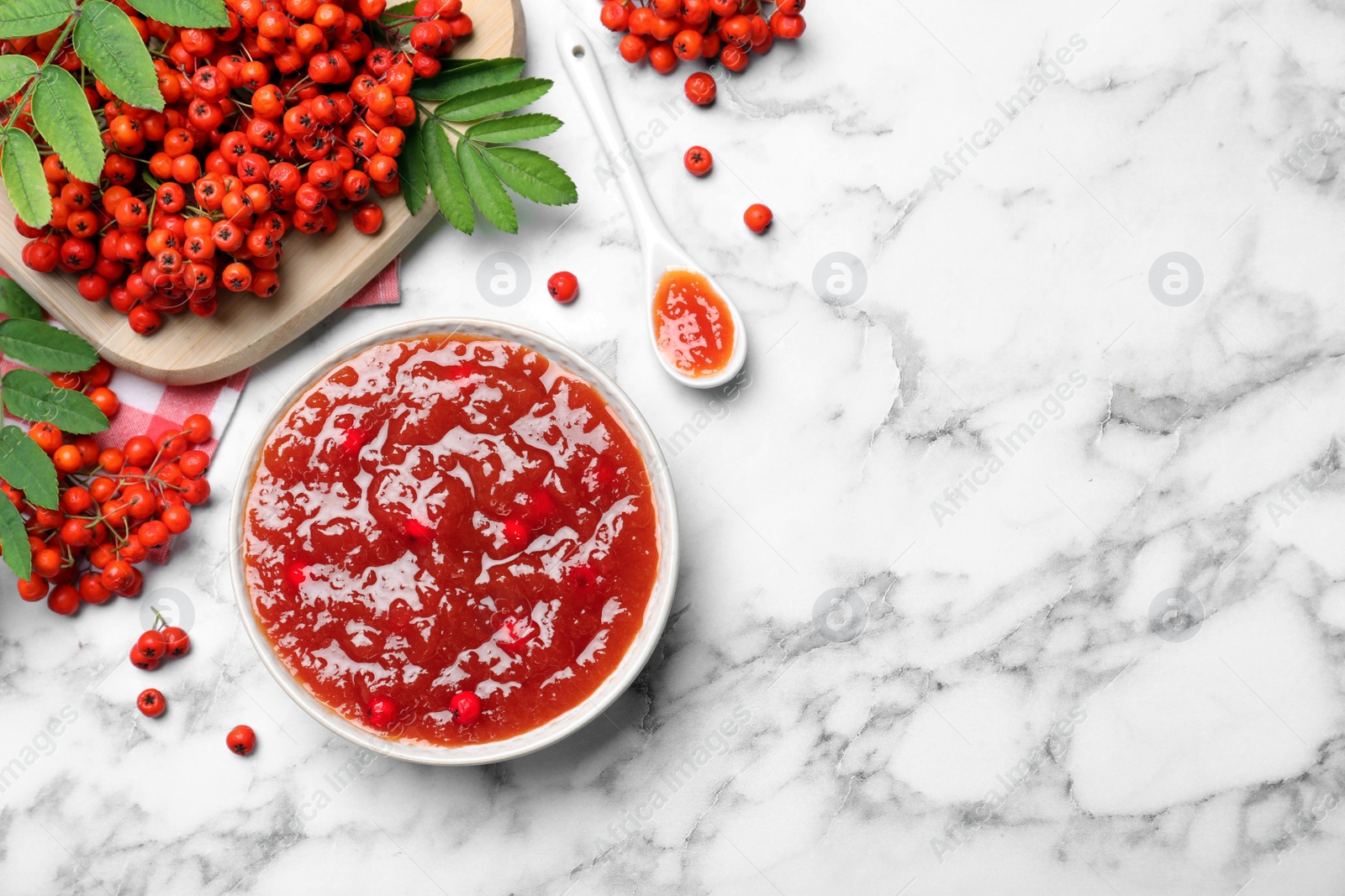 Photo of Flat lay composition with delicious rowan jam and berries on white marble table. Space for text