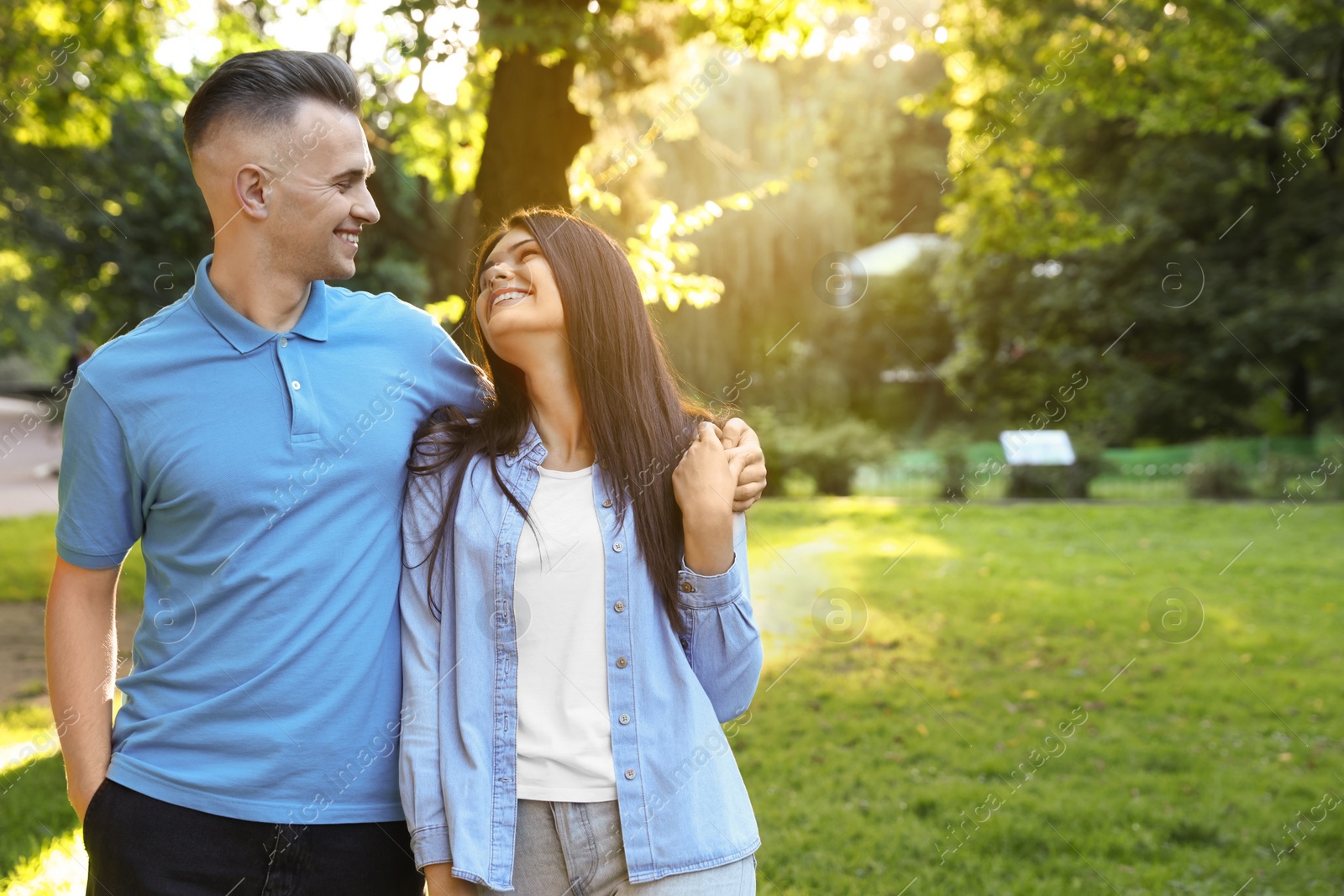 Photo of Affectionate young couple walking together in park, space for text