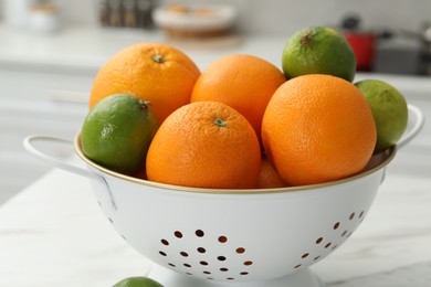 Photo of Colander with fresh fruits on table in kitchen, closeup