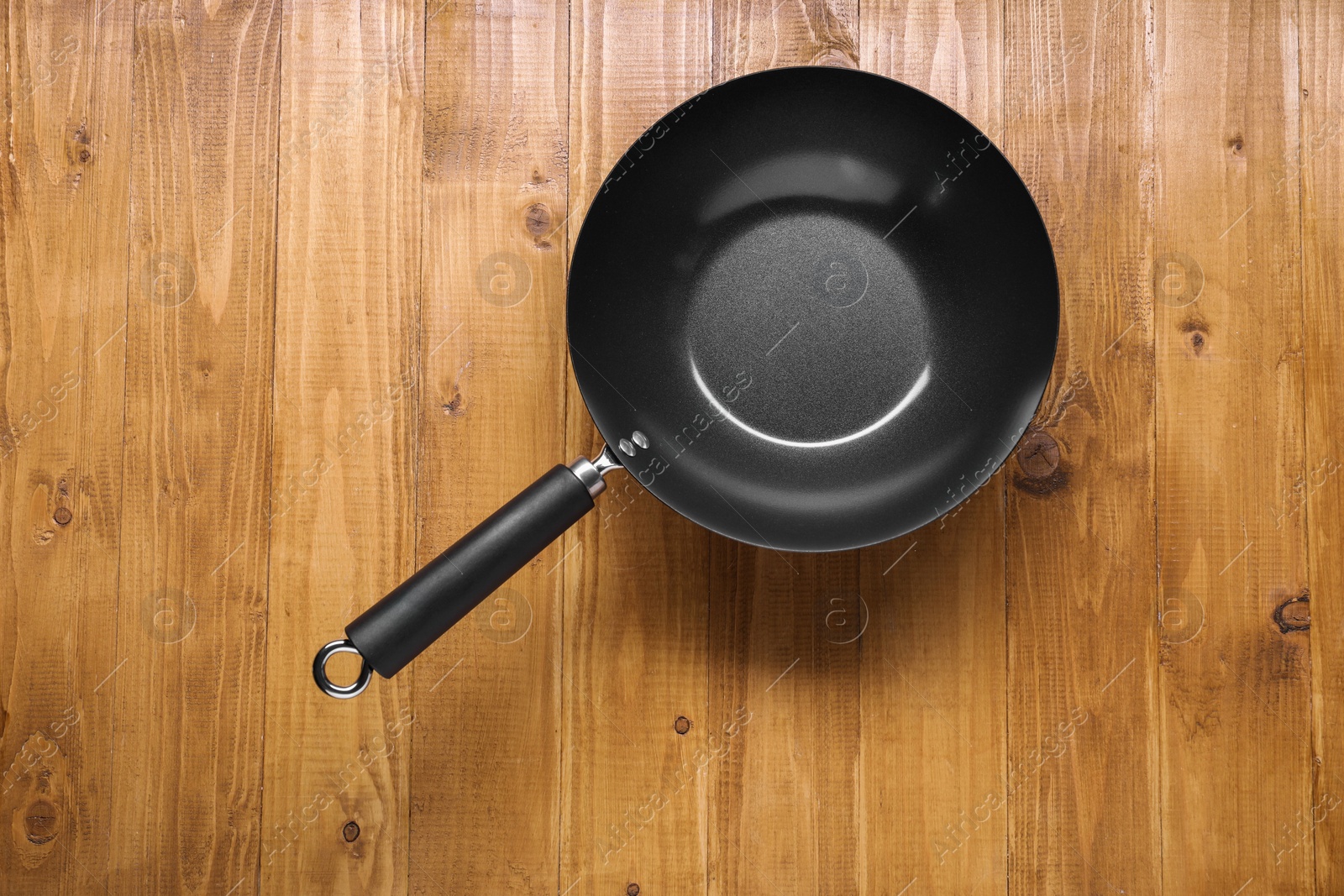 Photo of Empty iron wok on wooden table top view. Chinese cookware