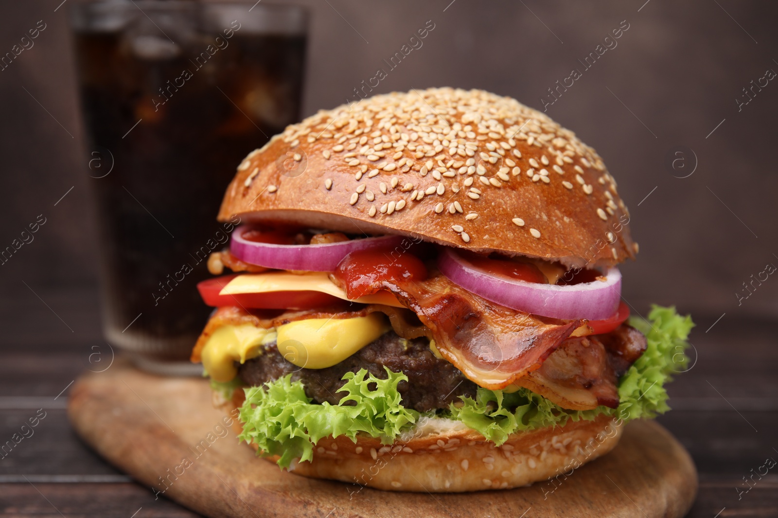 Photo of Delicious burger with bacon, patty and vegetables on wooden table, closeup