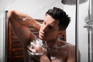 Photo of Man with mesh pouf taking shower at home