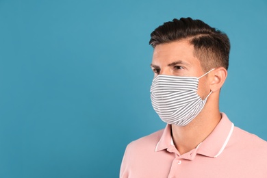 Photo of Man in protective face mask on blue background. Space for text