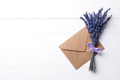 Photo of Bouquet of beautiful preserved lavender flowers and envelope on white wooden table, top view. Space for text