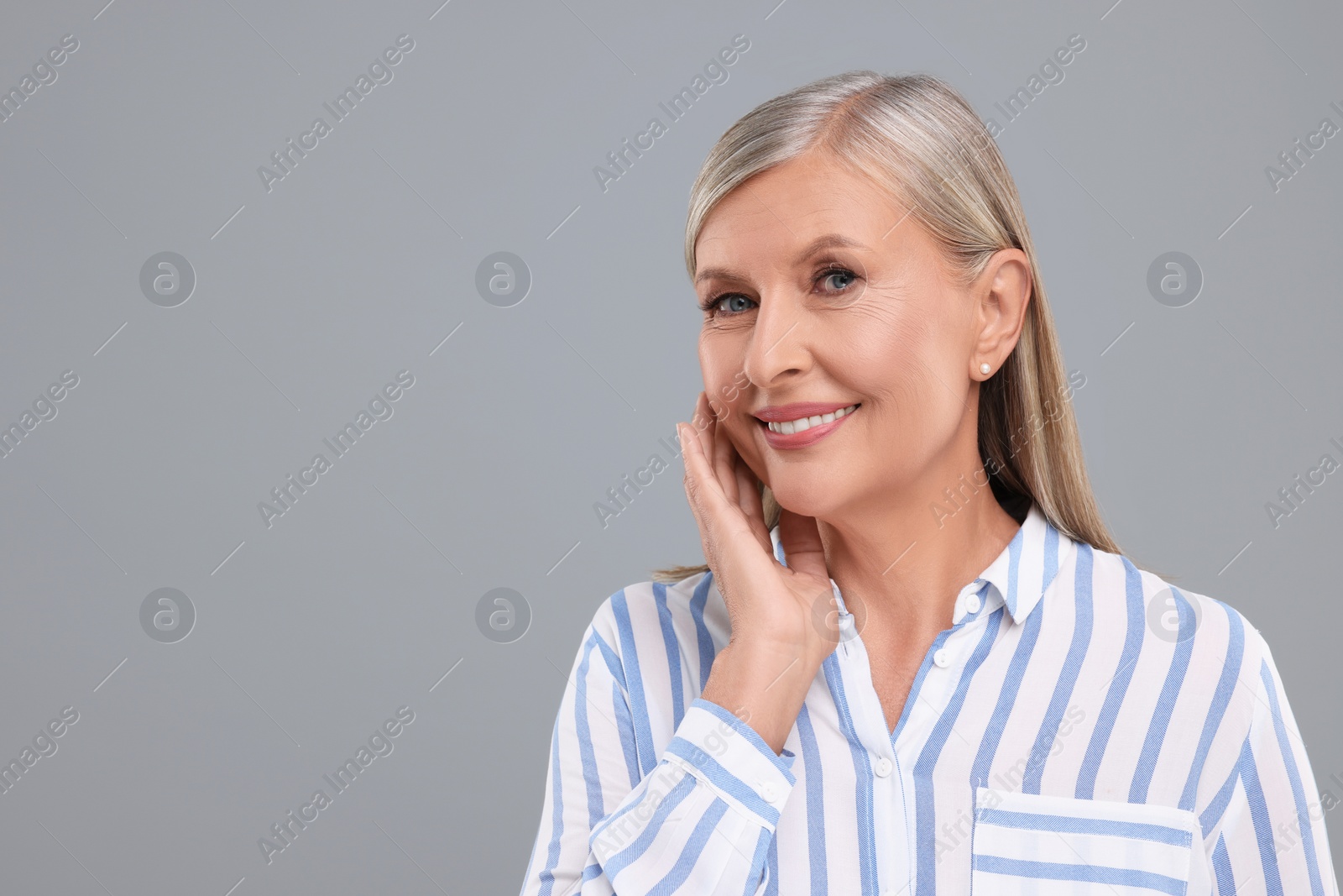 Photo of Portrait of beautiful middle aged woman on light grey background, space for text