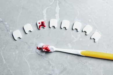 Photo of Flat lay composition of decorative teeth and toothbrush with blood on light grey marble table. Gum inflammation