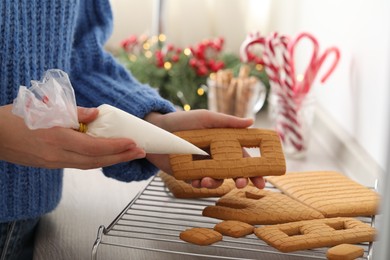 Photo of Woman making gingerbread house at wooden table, closeup