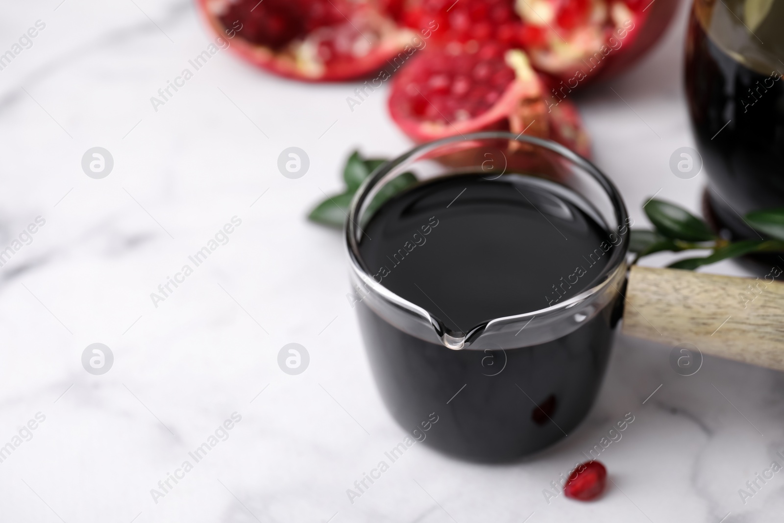 Photo of Tasty pomegranate sauce on white marble table, closeup. Space for text